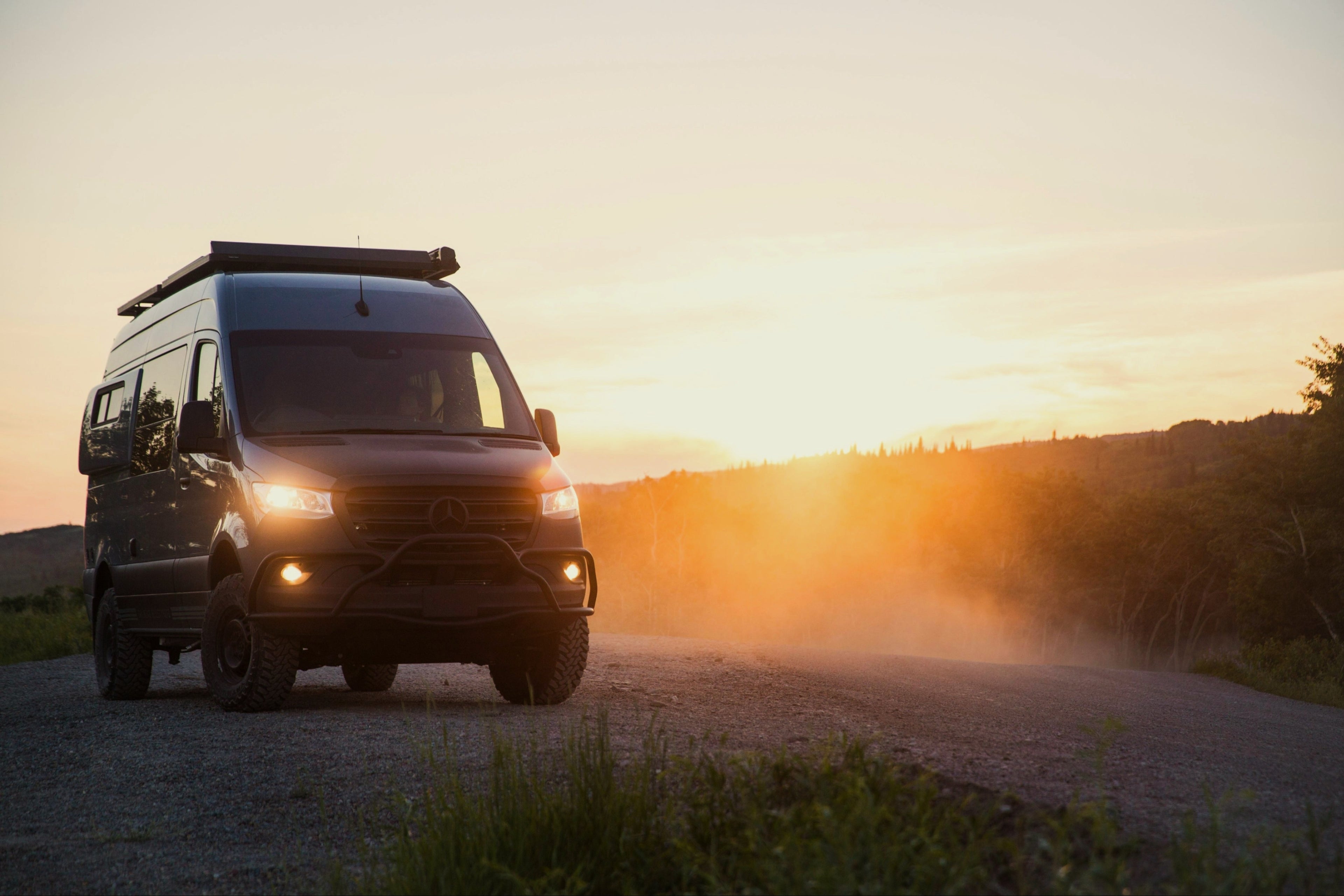 Van on a dirt road with a sunset in the background